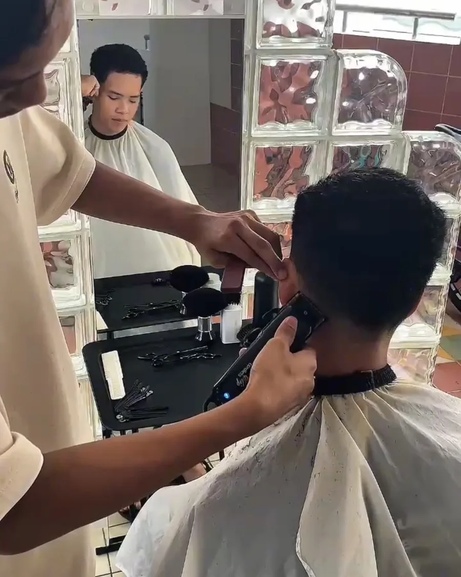 Ihsan running clippers along a client's neckline, the cut reflected in the mirror behind